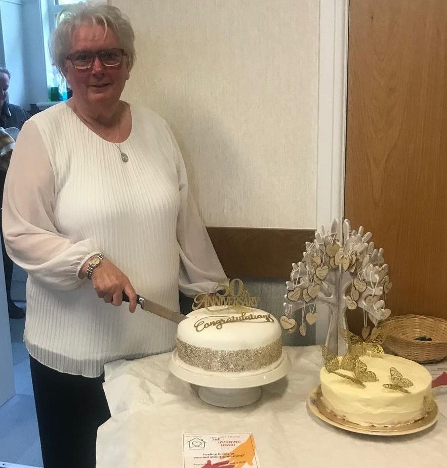 A woman is cutting a cake on a table.