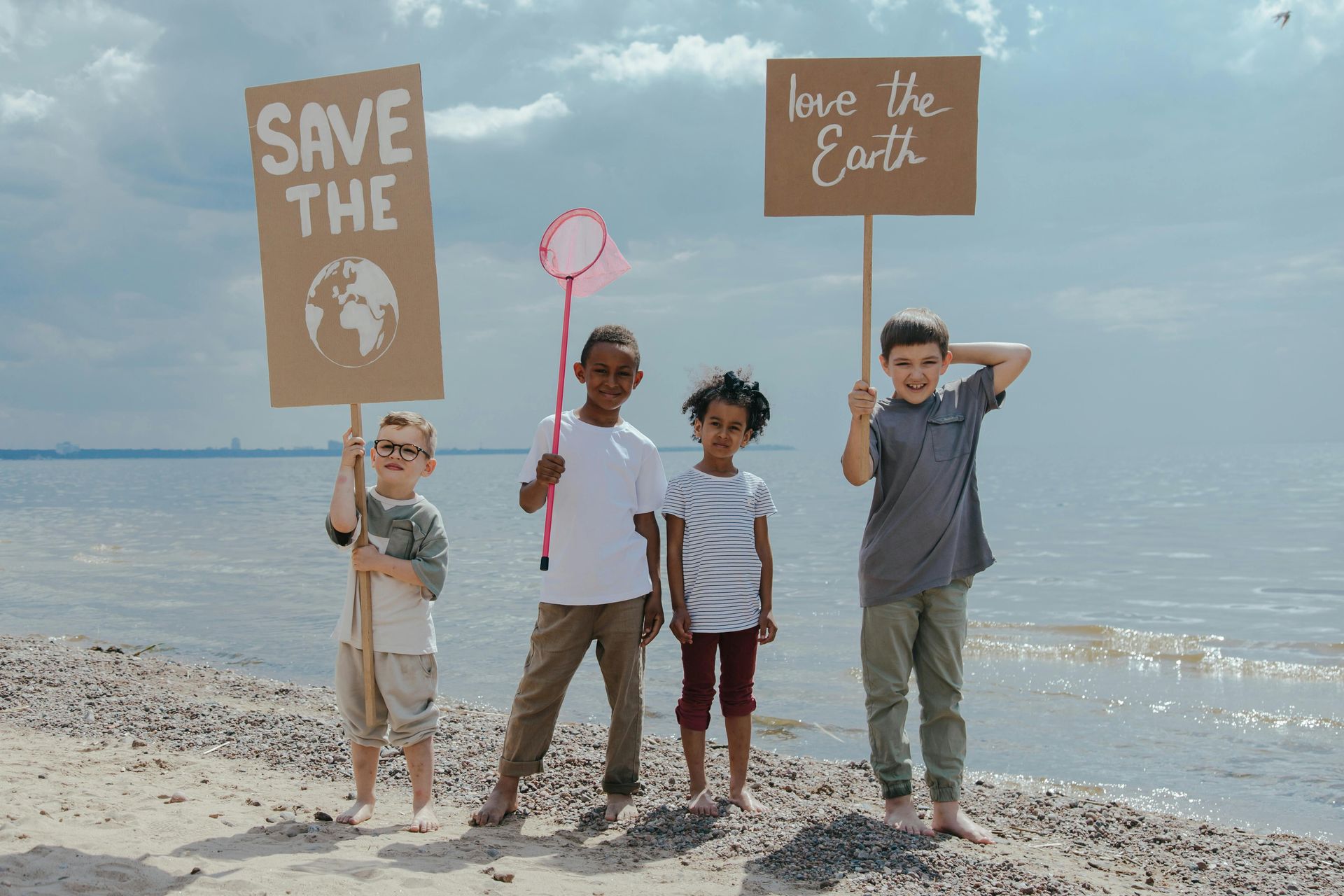 Four children on a beach hold signs: 