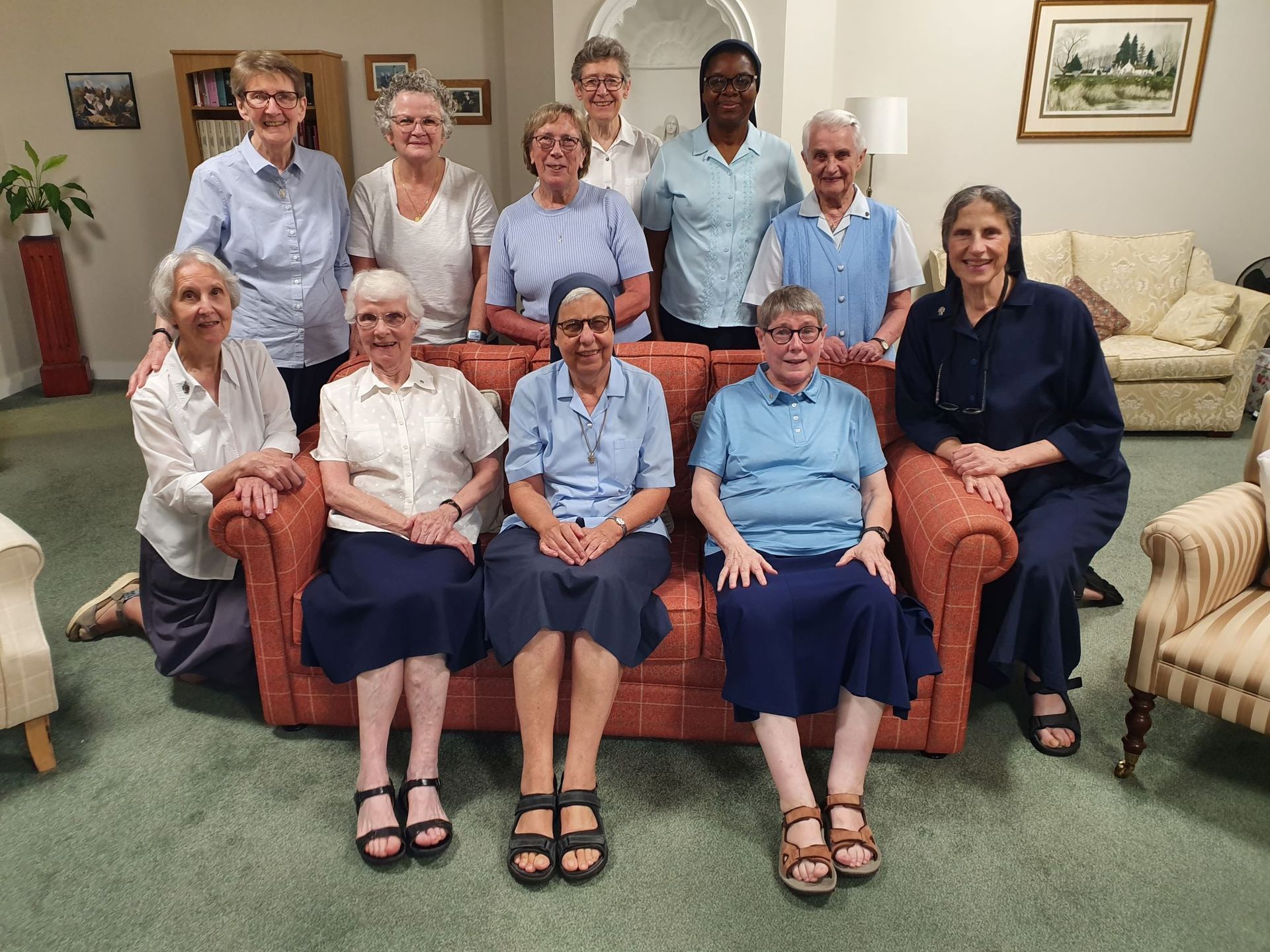 a group of Daughters of Charity are posing for a picture in a living room .