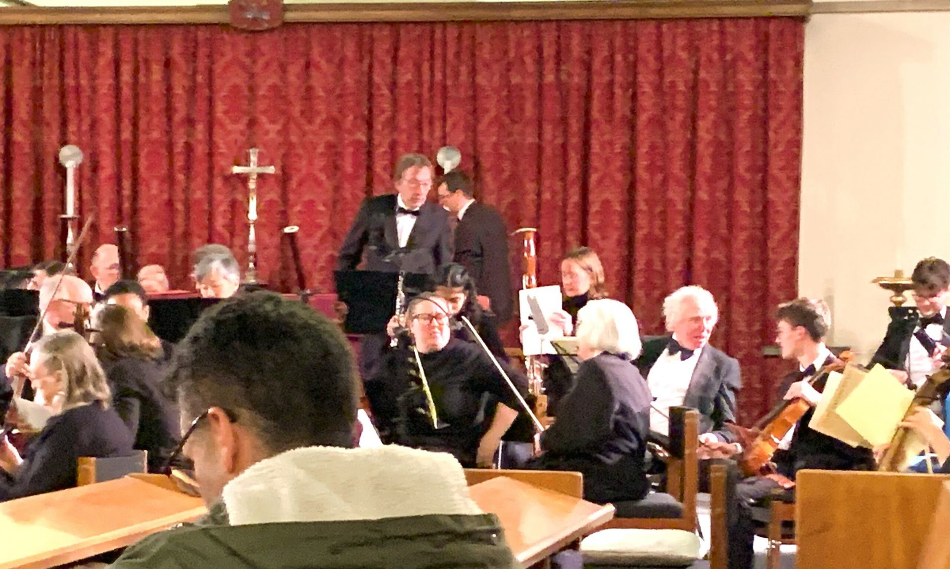 a group of people are sitting in a church watching an orchestra perform .