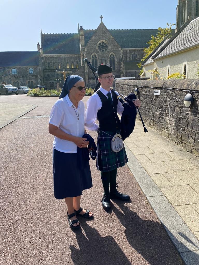 a man in a kilt is playing a bagpipe next to a woman .