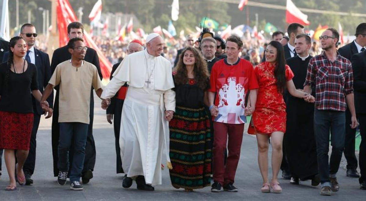 Pope Francis is standing in front of a crowd and waving.