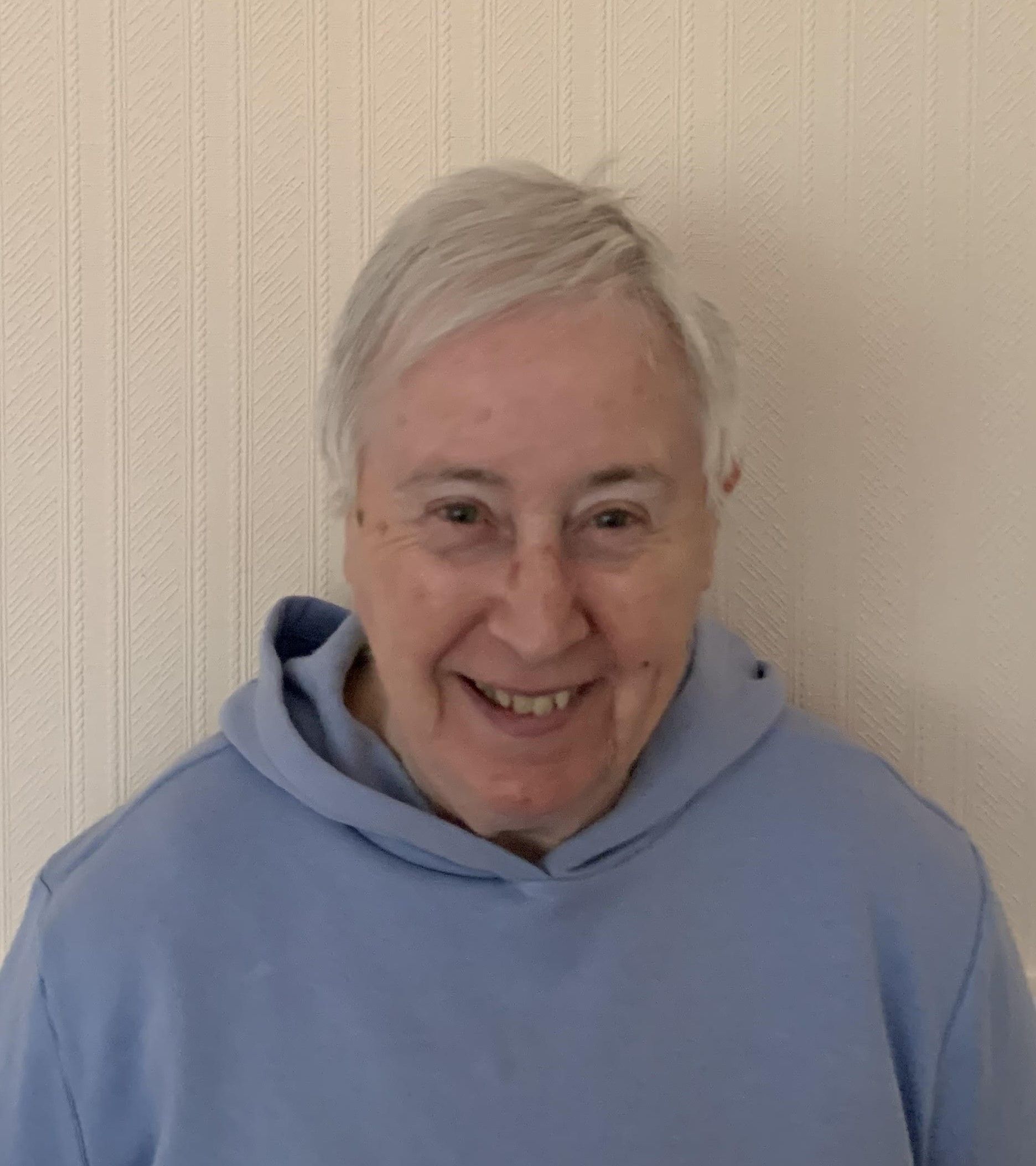 a woman wearing a blue hoodie is smiling for the camera.