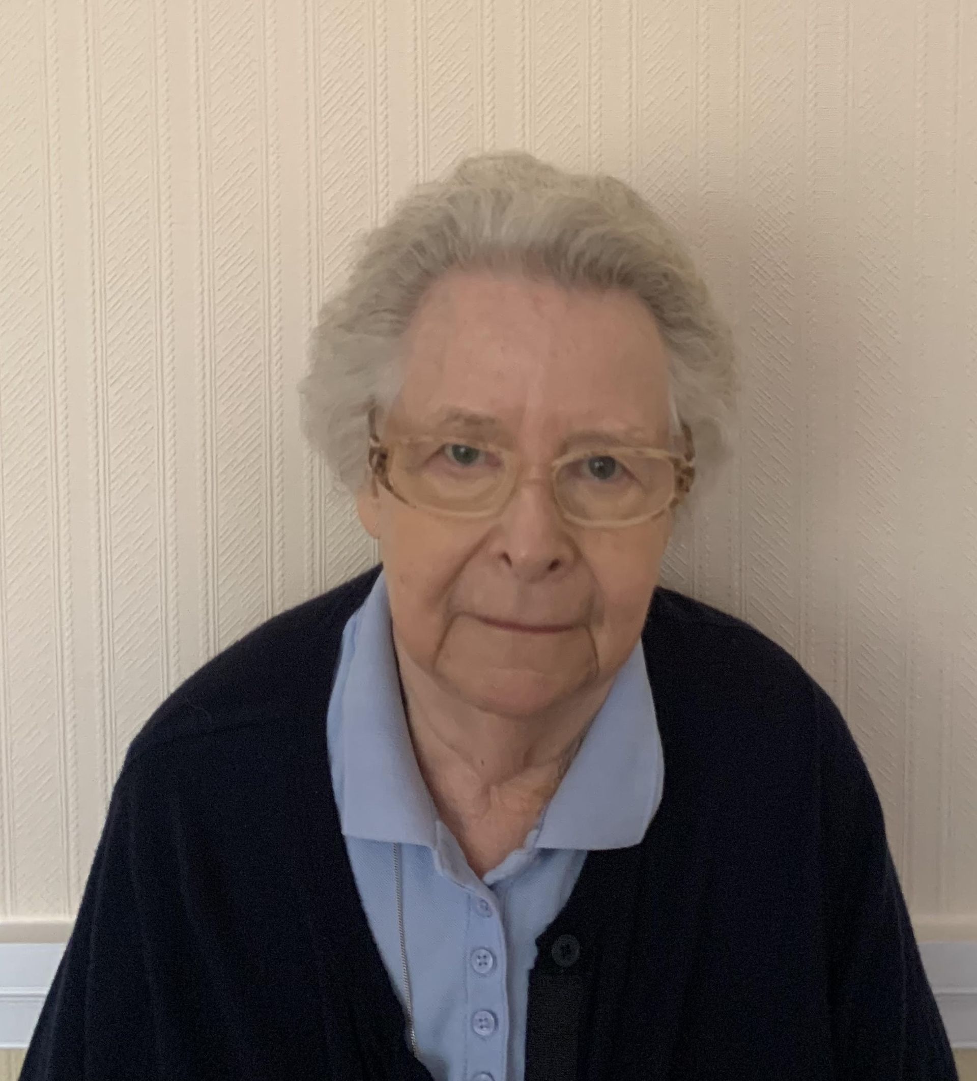 an elderly woman wearing glasses and a blue shirt