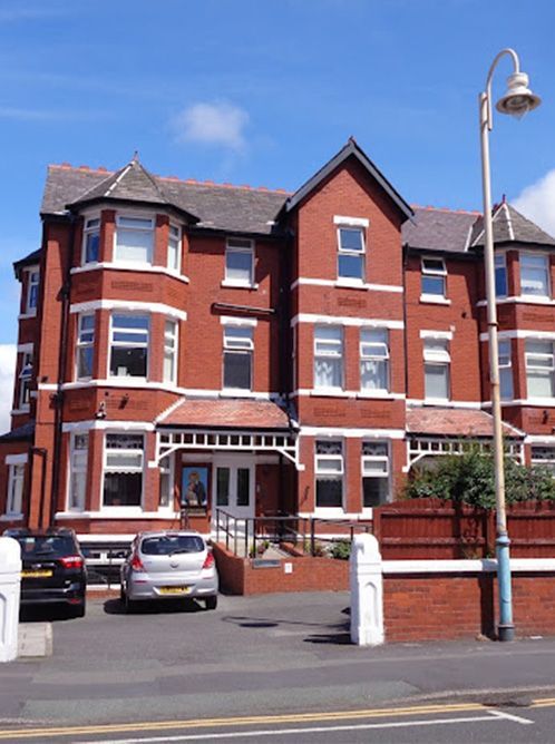 a large red brick building with a wooden fence in front of it