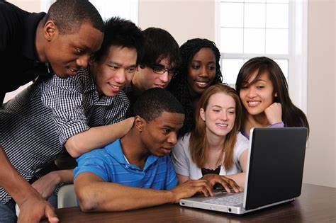 A group of young people are looking at a laptop computer.