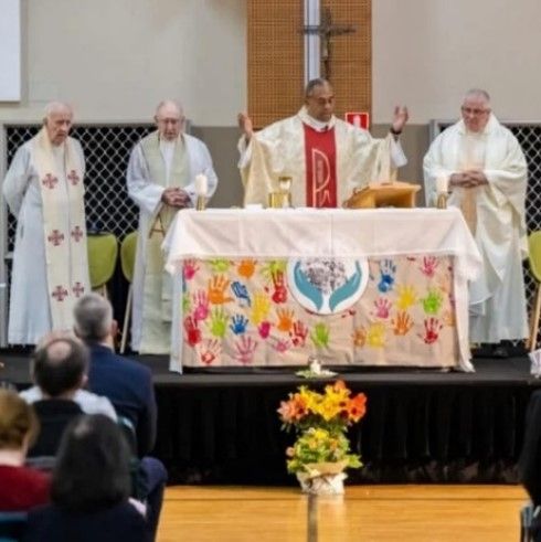 A group of priests are standing around an altar with the letter p on it