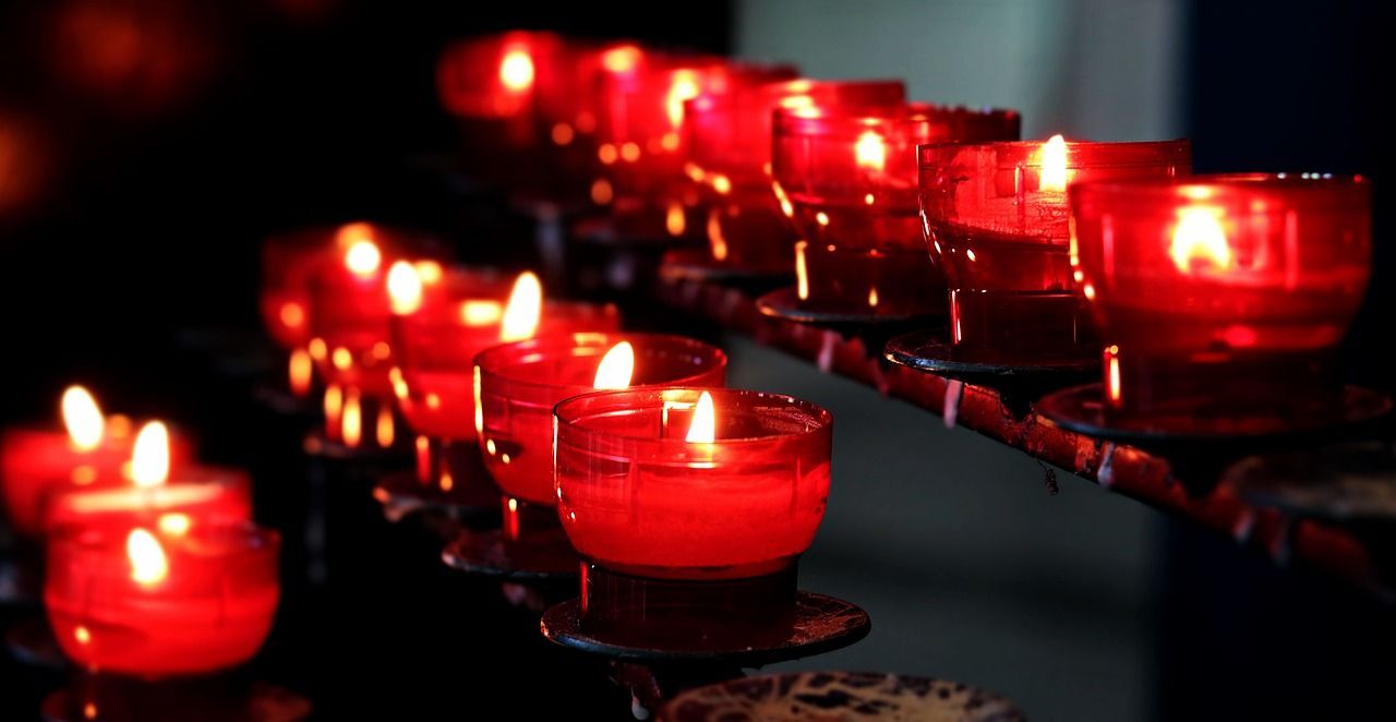 a row of red votive candles are lit up in a dark room 