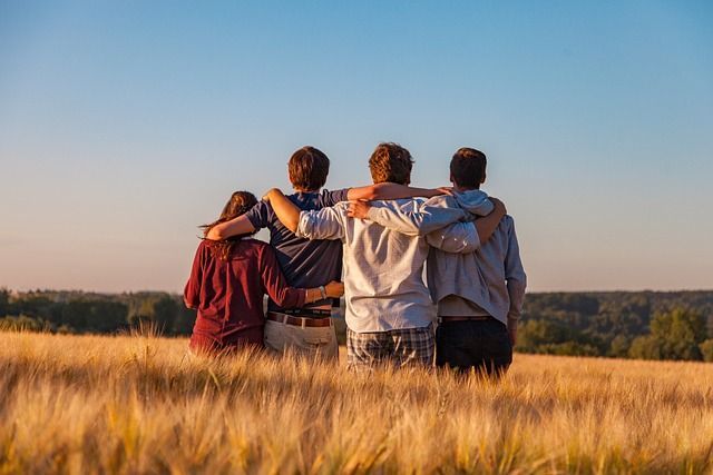 A group of people are standing in a field with their arms around each other.