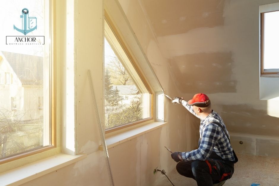 Contractor working on drywall in an attic with many large windows for a residential home. 