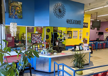 Colorful school or office reception desk with “WELCOME” sign, plants, and bulletin boards