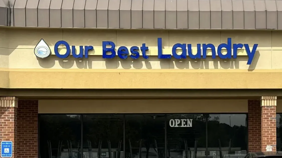 Our Best Laundry storefront with blue sign and an “OPEN” notice in the window