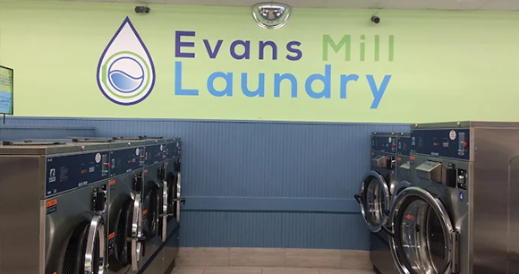 Evans Mill Laundry sign above rows of front-load washers in a laundromat
