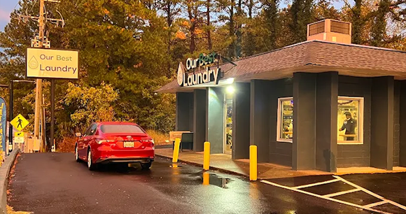 Our West Laundry storefront at dusk with a red car and yellow bollards in front