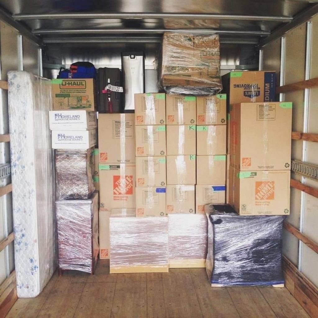 Boxes and wrapped items fill the inside of a moving truck, ready to be transported.