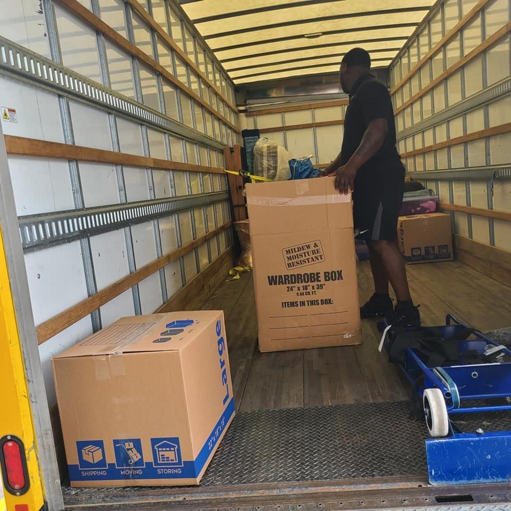 Man loading cardboard boxes into a moving truck. Interior view.