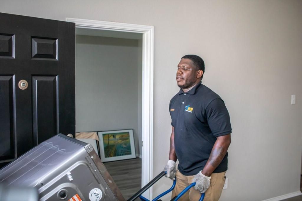 Man moving an appliance with a hand truck through a doorway.