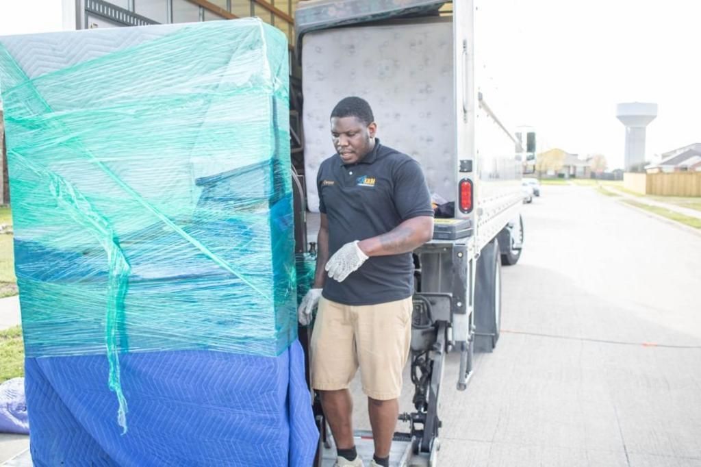 Man loading a wrapped object into a moving truck. Outdoors on a sunny day.