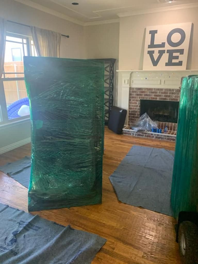 Furniture wrapped in green plastic inside a room, protected for moving.