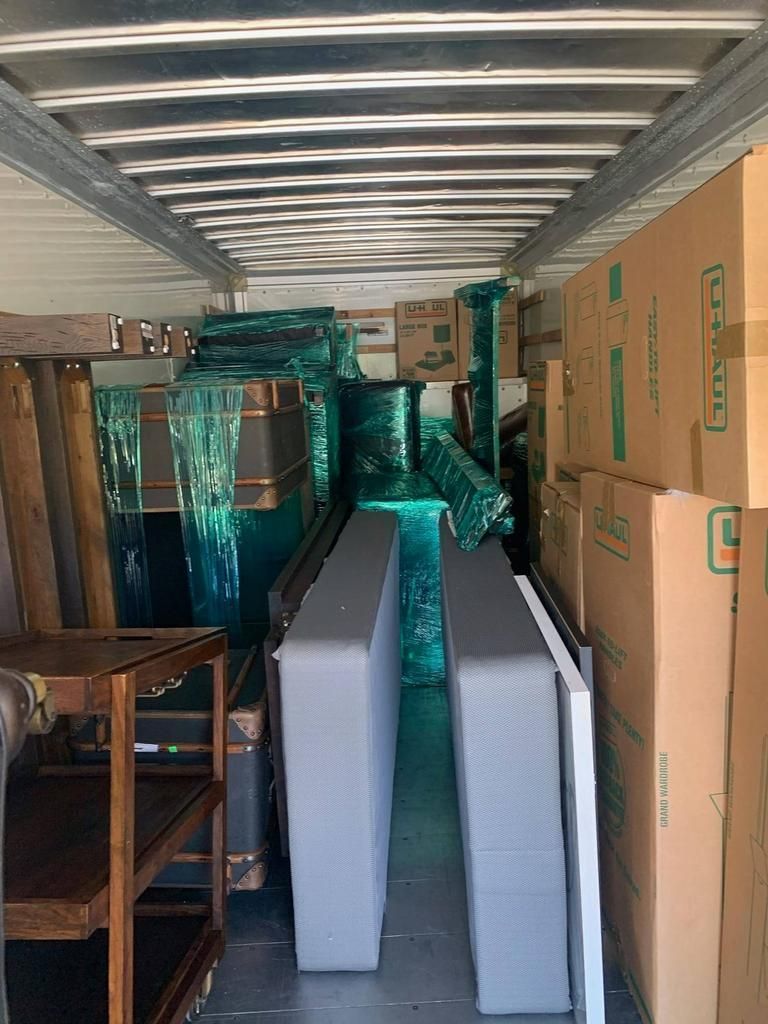 Interior of a moving truck packed with furniture and boxes, including mattresses, tables, and wrapped items.
