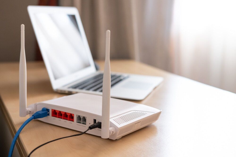 A Router is Sitting on a Wooden Table Next to a Laptop — Frontier Connect in Roma, QLD