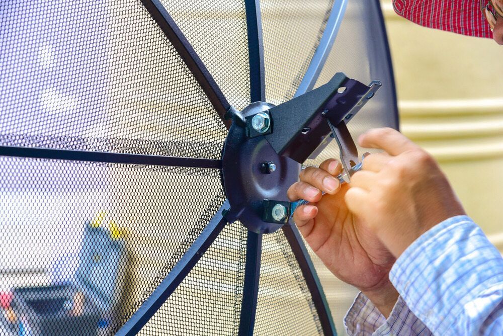 A Man is Fixing a Satellite Dish With a Wrench — Frontier Connect in Gatton, QLD