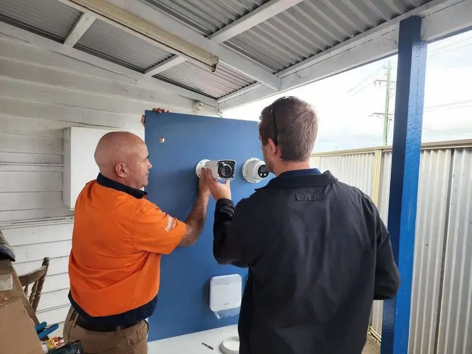 Two Men Are Installing Security Cameras on a Wall — Frontier Connect in Newtown, QLD
