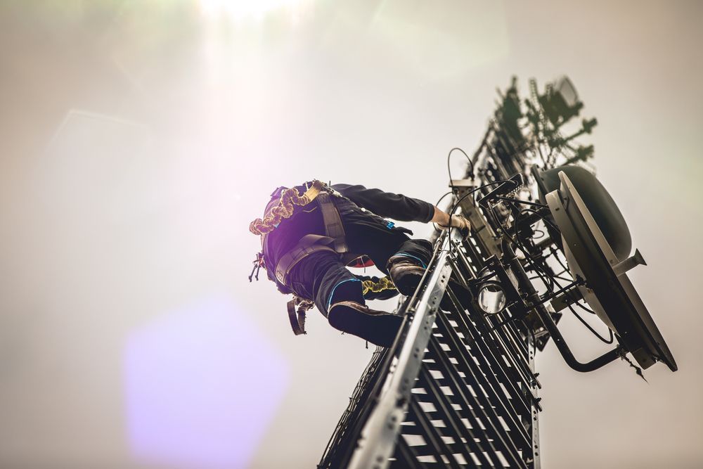 A Man is Standing on Top of a Cell Phone Tower — Frontier Connect in Roma, QLD