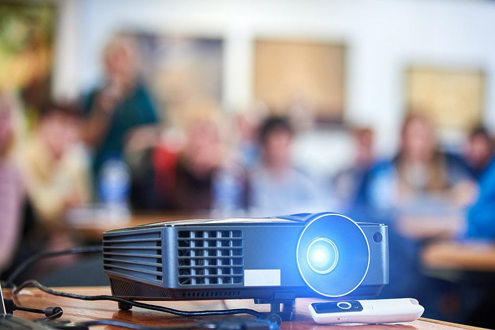 A Projector is Sitting on a Table in Front of a Group of People — Frontier Connect in Dalby, QLD