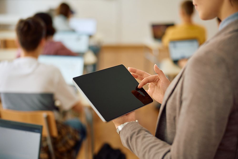 A Woman is Holding a Tablet in Front of a Group of Students in a Classroom — Frontier Connect in Roma, QLD