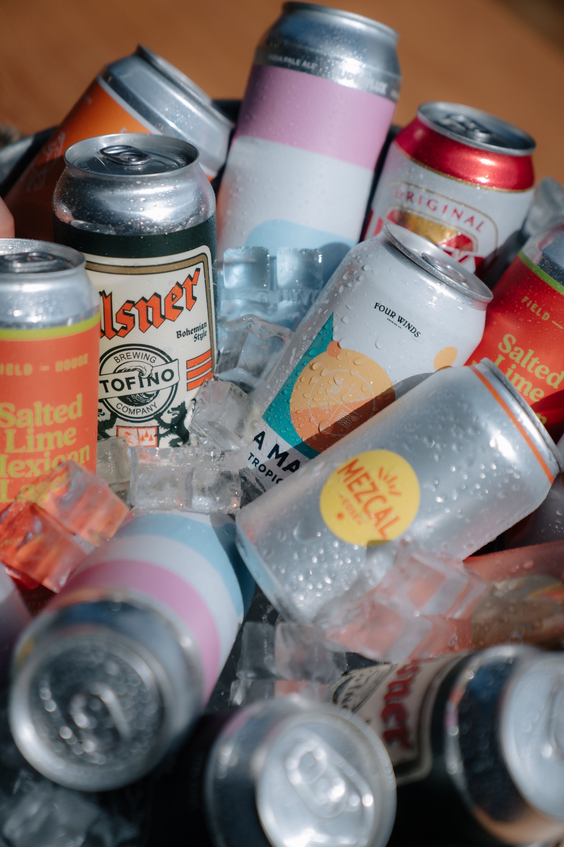 A variety of colorful beverage cans nestled in a pile of ice cubes.