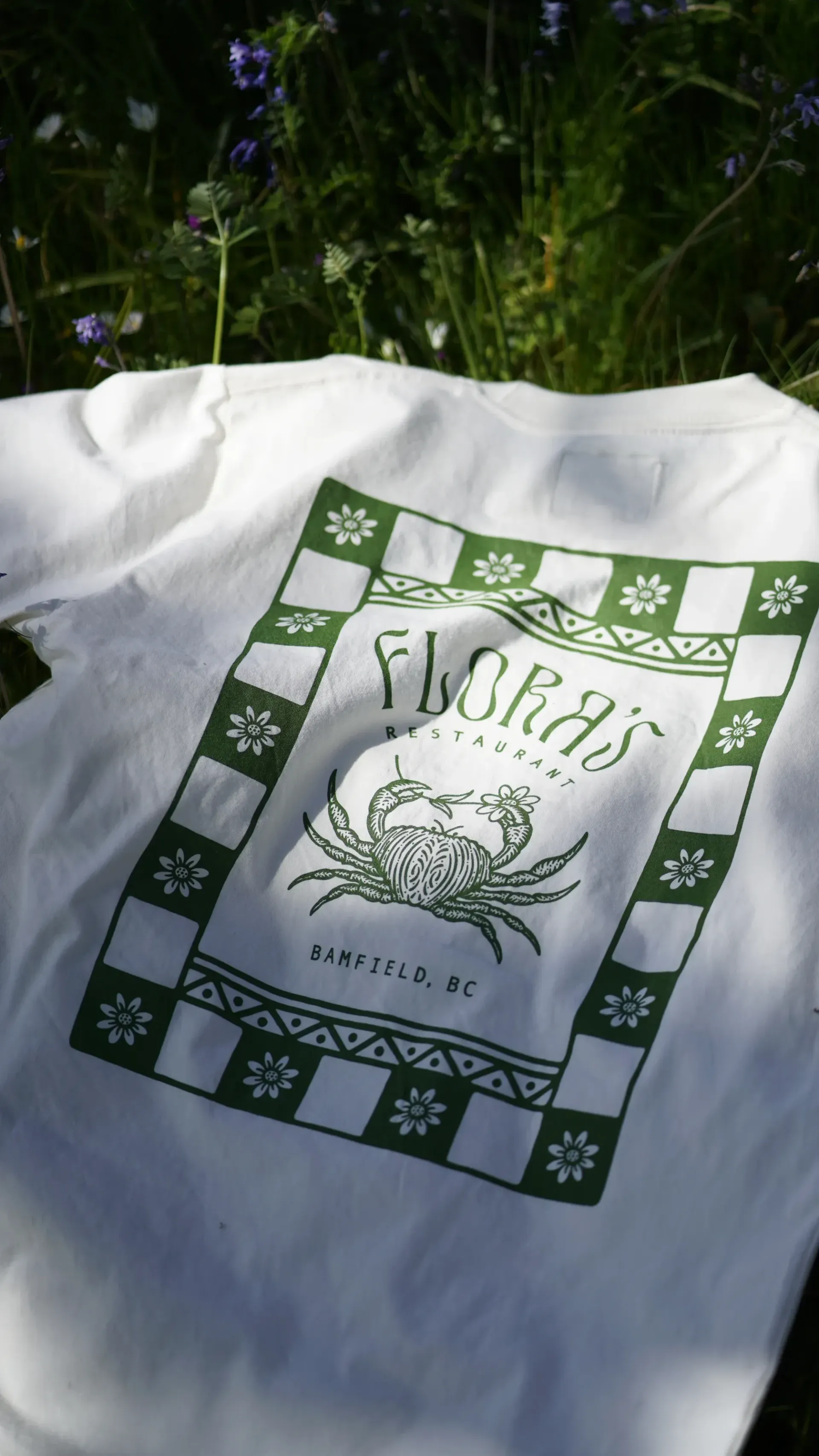 A white t-shirt with a green and white checkered pattern and a crab on it.