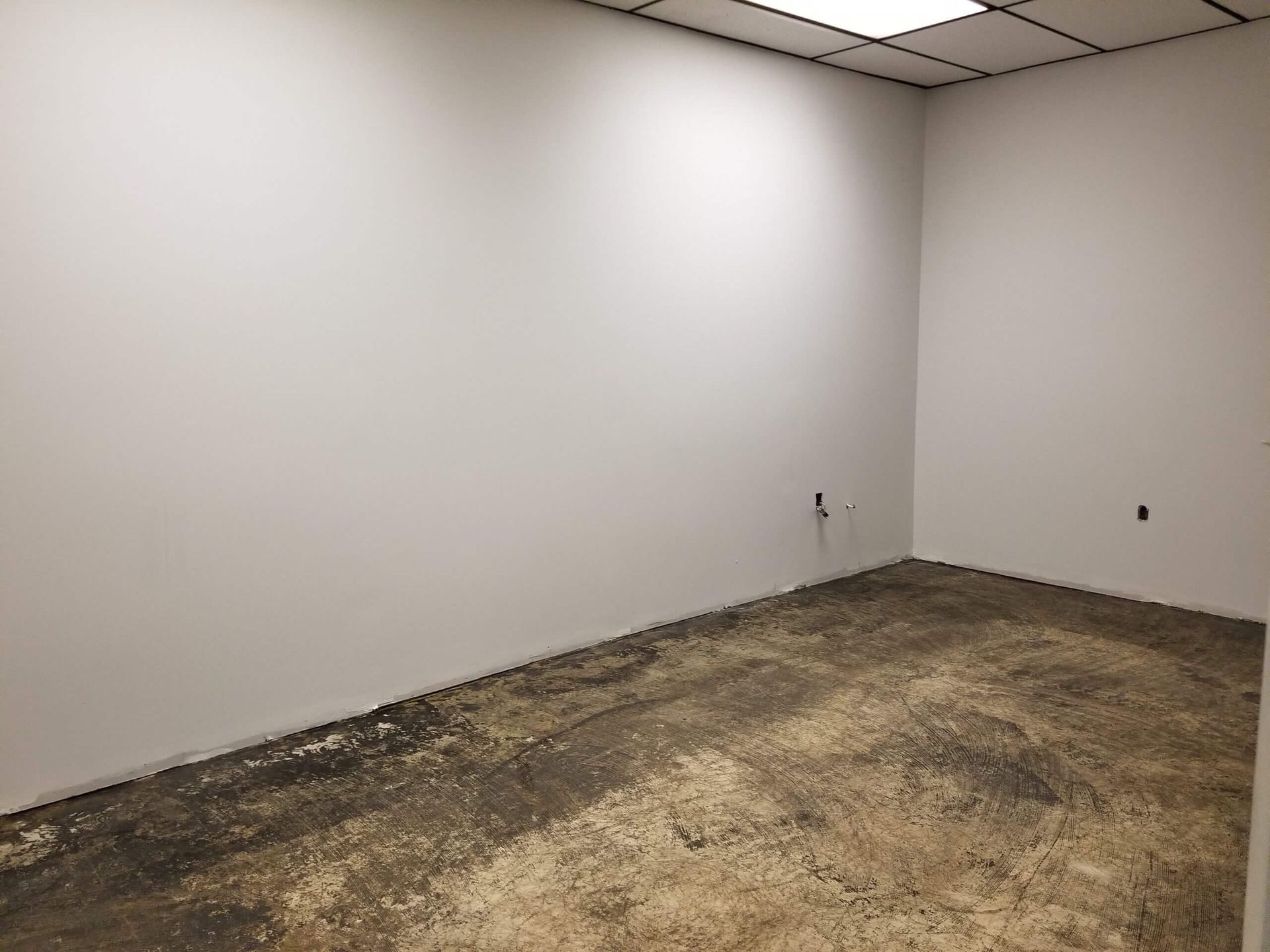 An empty room with a dirty floor and white walls