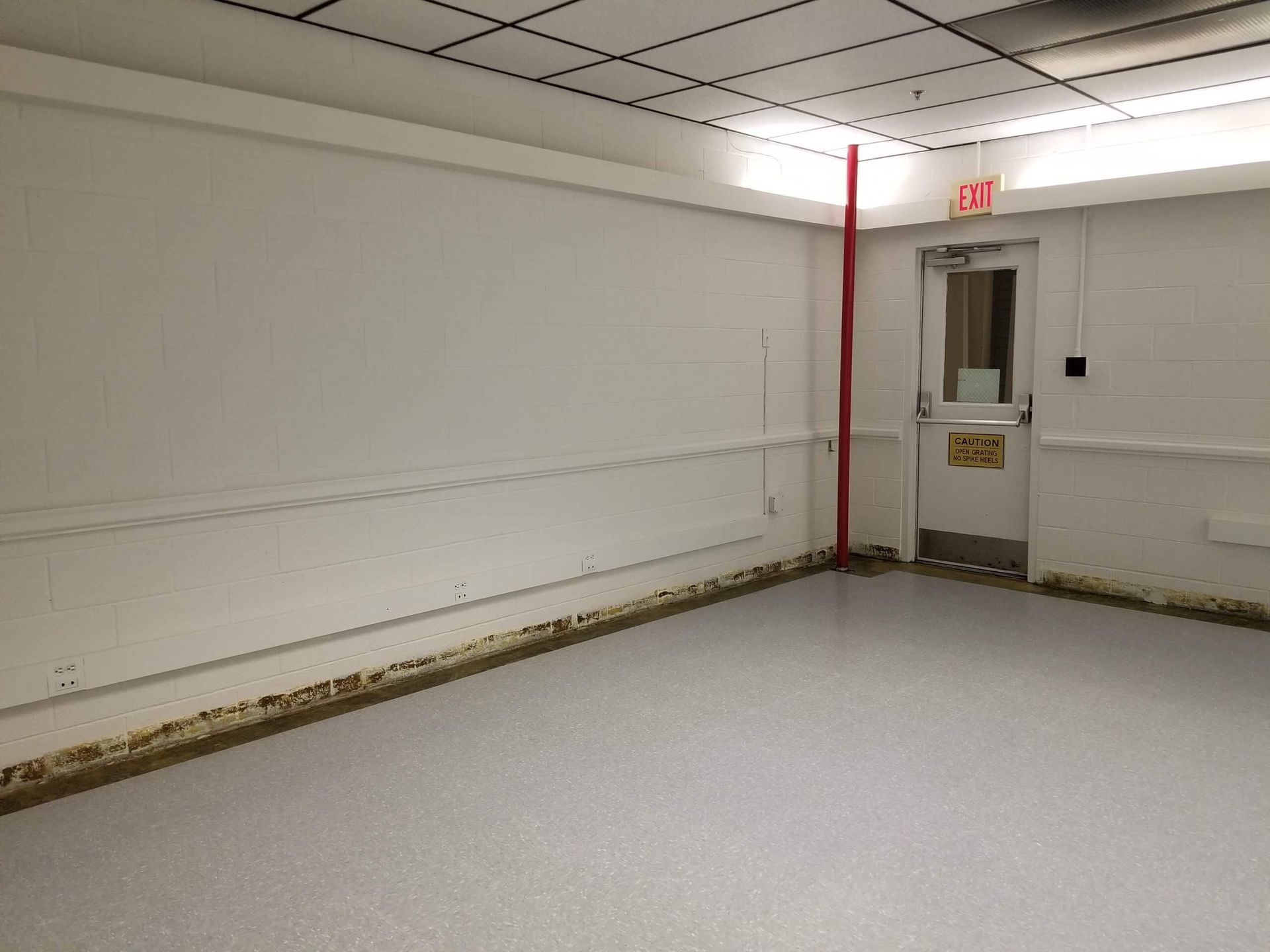 An empty room with a red exit sign on the door