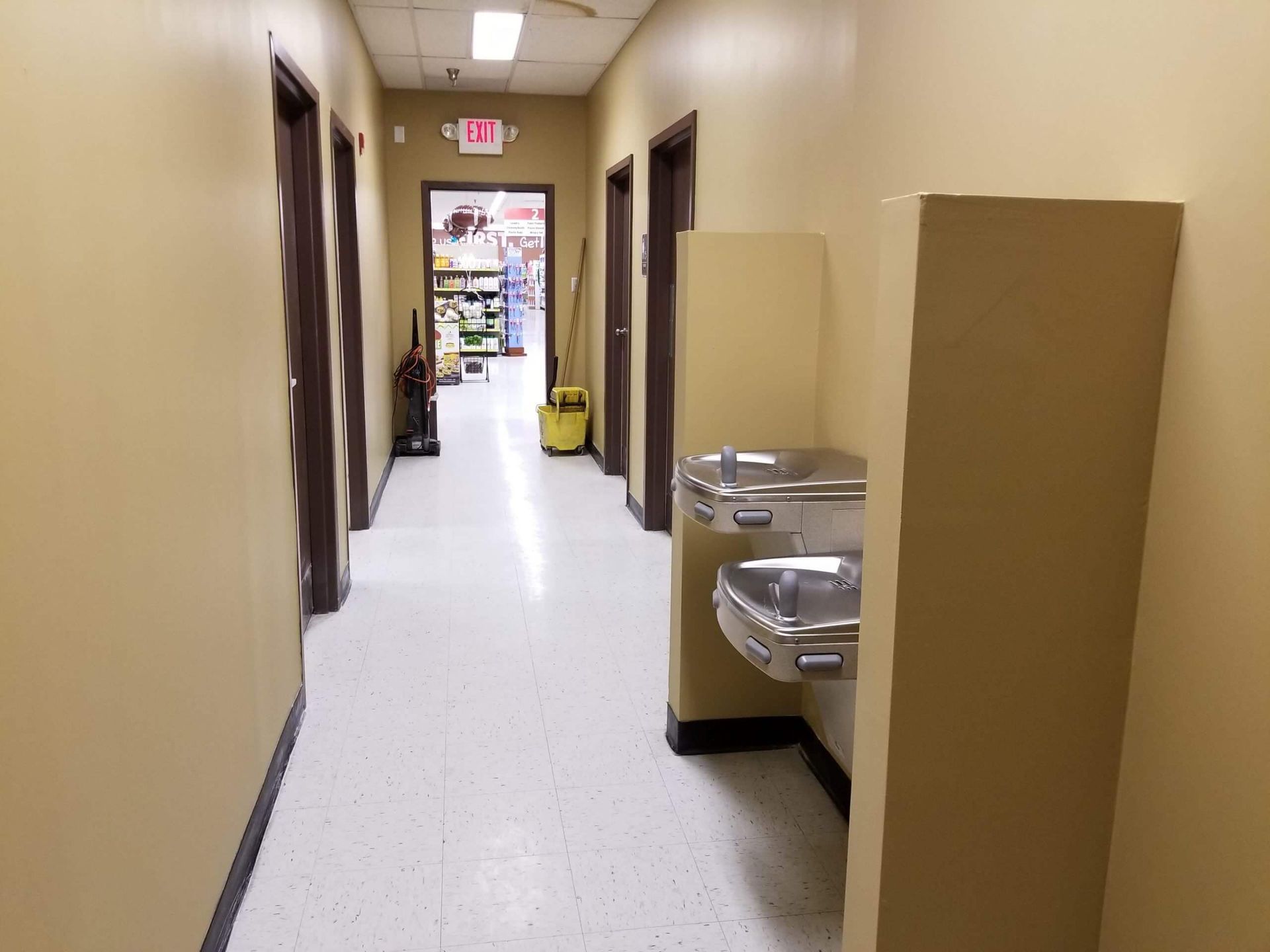 A hallway with two water fountains and an exit sign