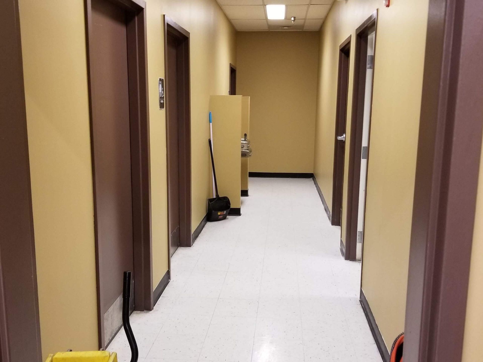 A long hallway with a yellow mop on the floor