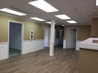 A large empty room with hardwood floors and ceiling lights.