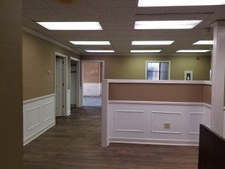 A large empty room with hardwood floors and a ceiling light.
