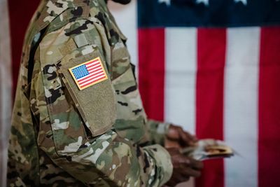 A soldier is holding money in front of an american flag.