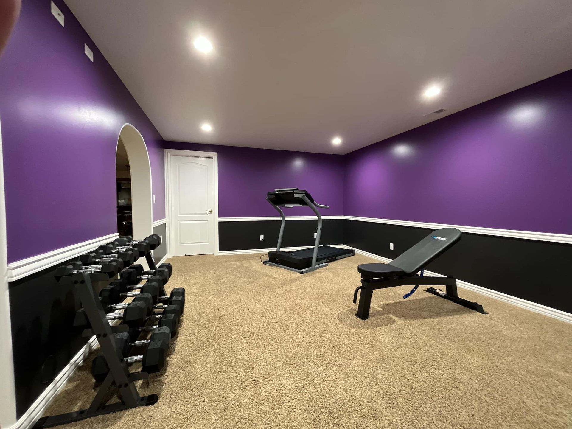 A basement gym with purple walls and a treadmill.