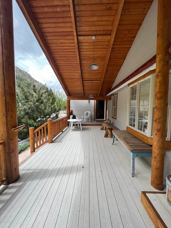 A large porch with a wooden railing and a bench.