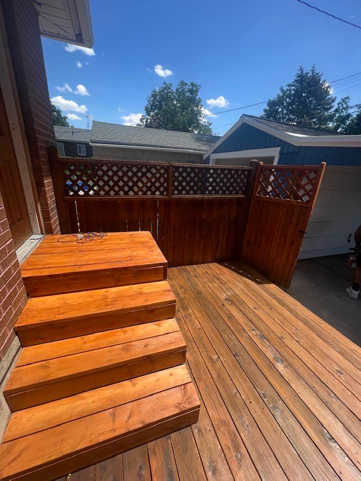 A wooden deck with stairs and a fence in front of a house.