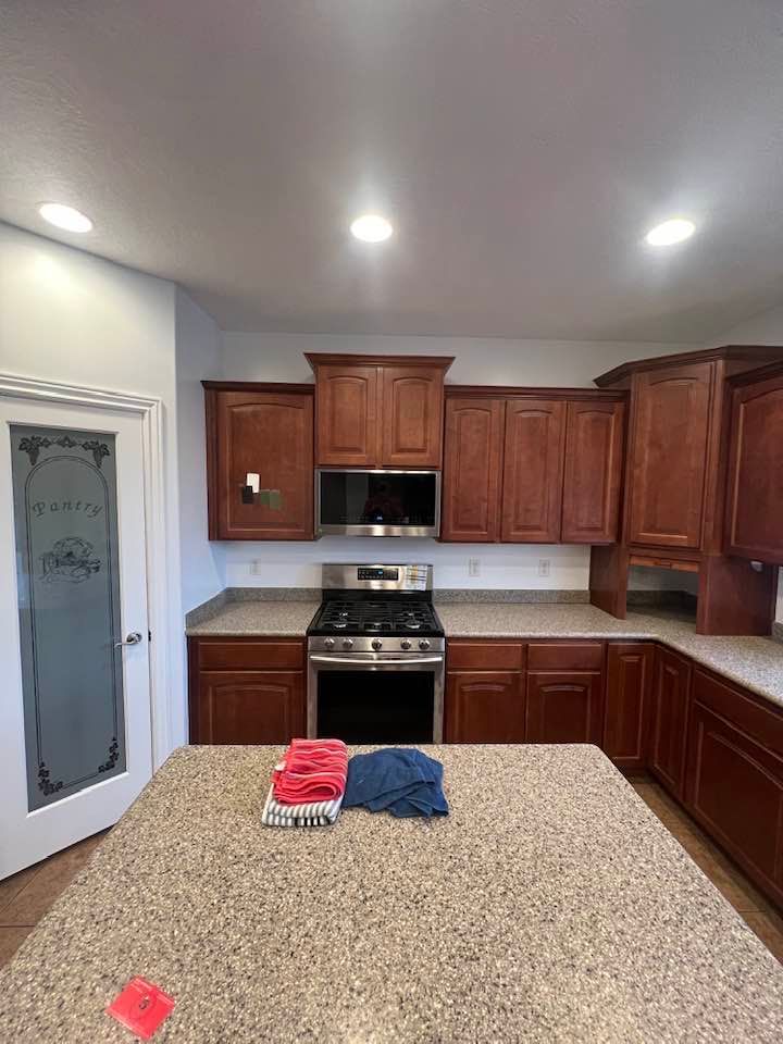 A kitchen with wooden cabinets , granite counter tops , stainless steel appliances and a large island.