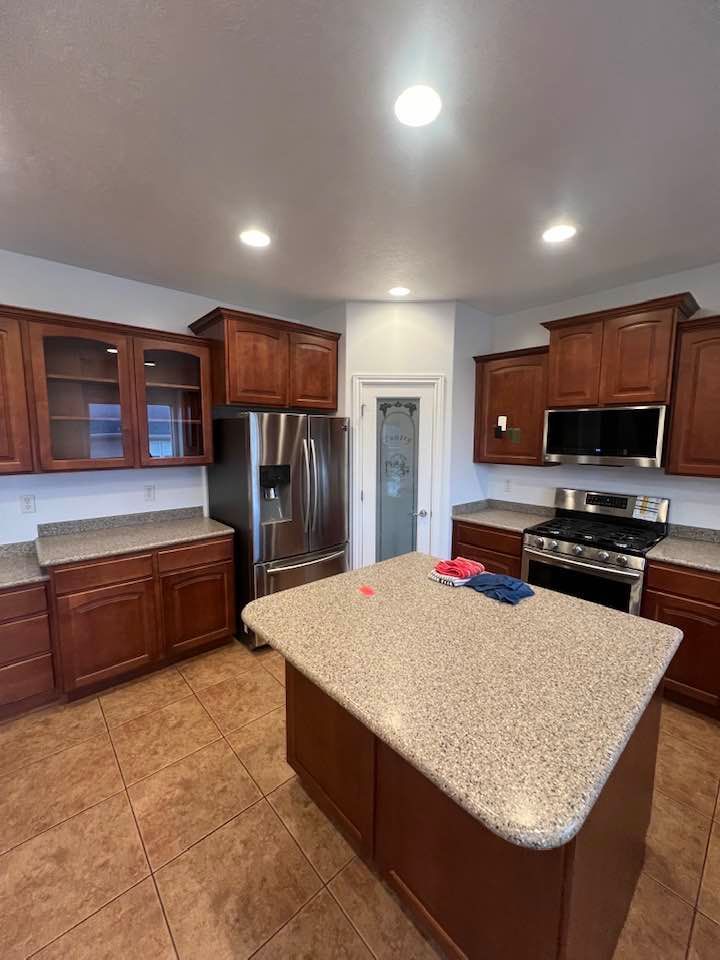 A kitchen with stainless steel appliances , granite counter tops , and wooden cabinets.
