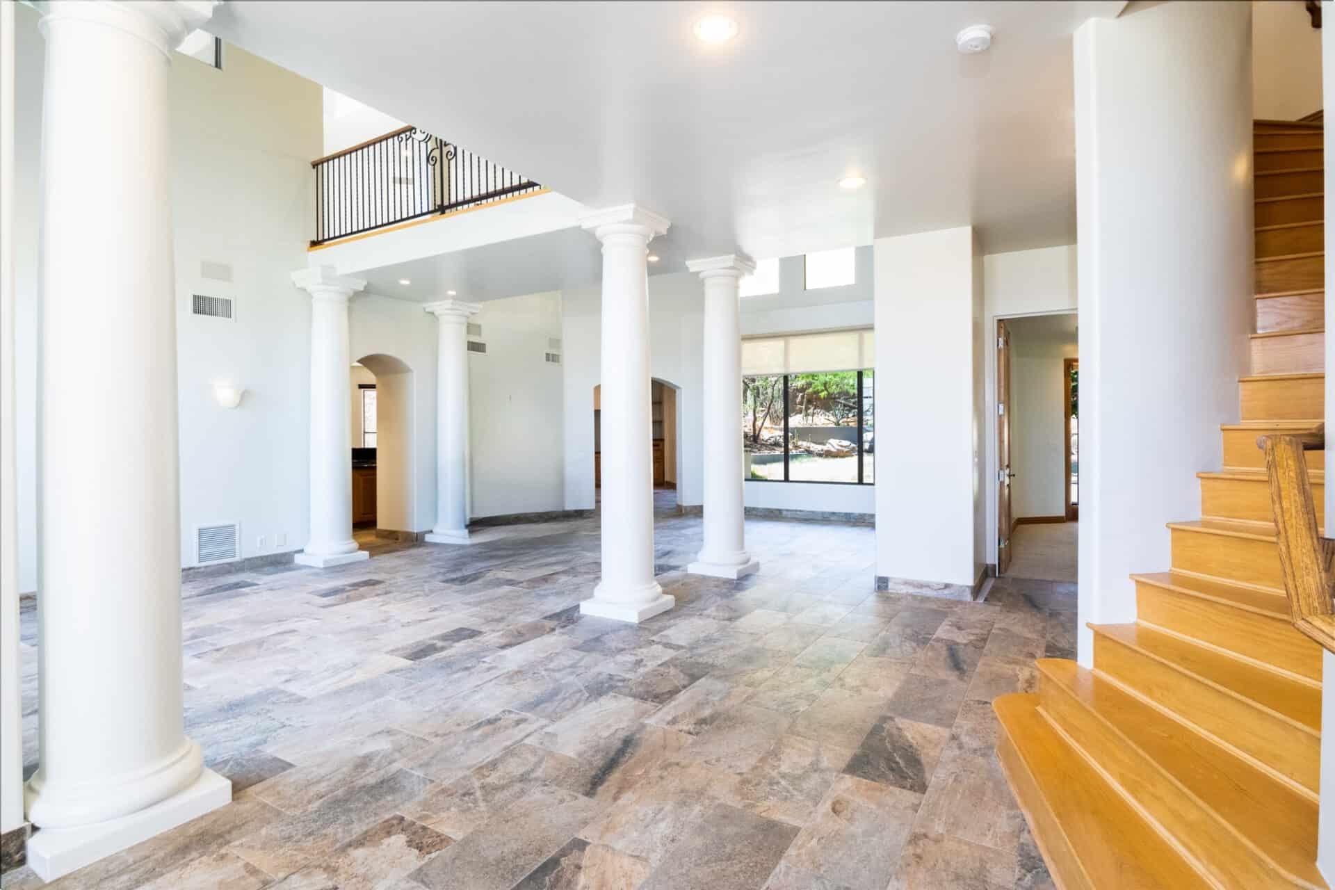A large empty room with columns and stairs in a house.