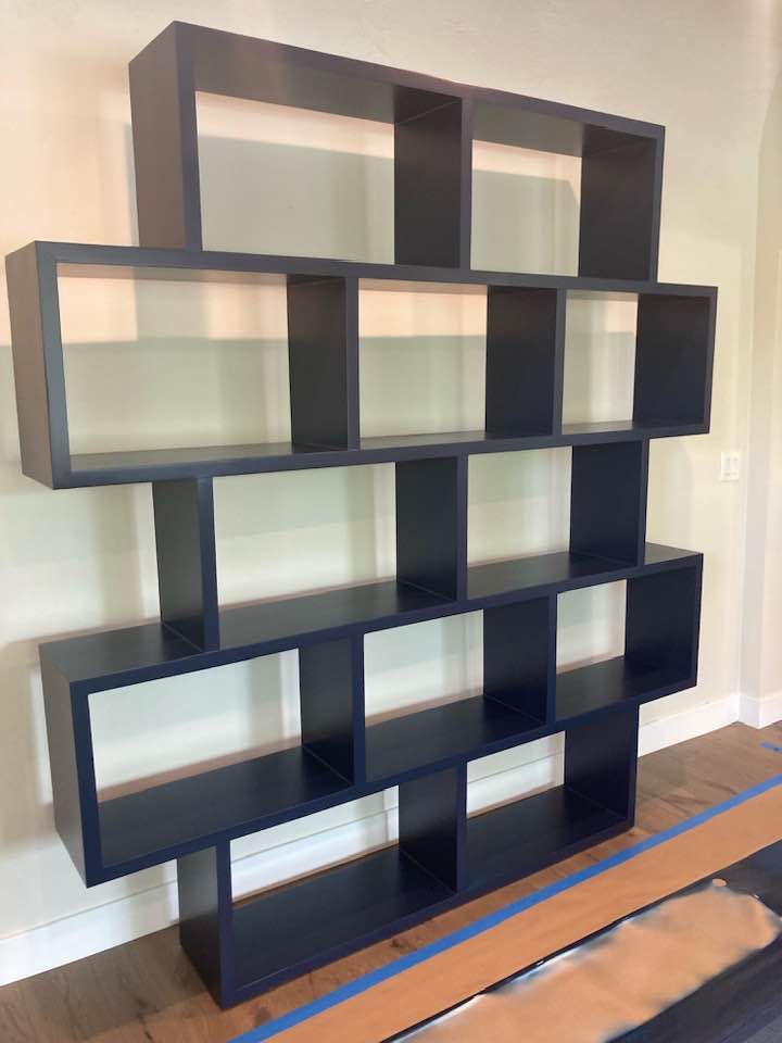 A black bookshelf is sitting on a wooden floor in a room.