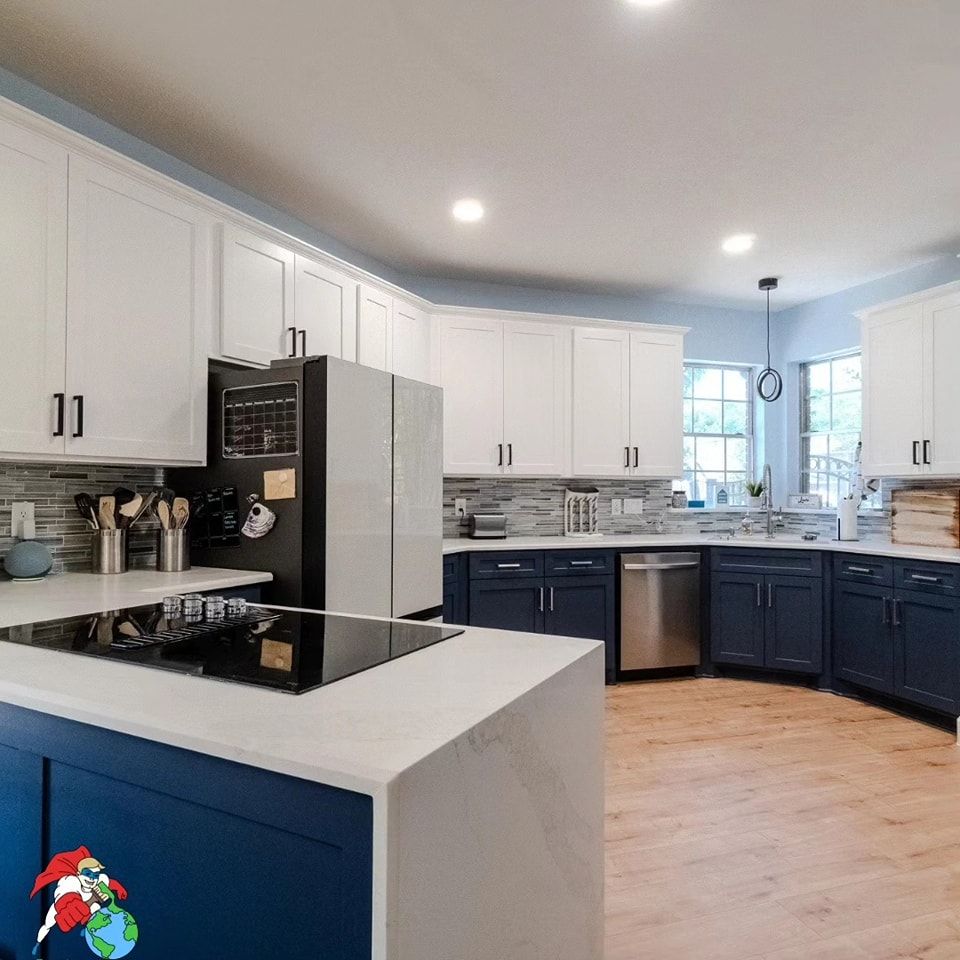 A kitchen with blue cabinets , white cabinets , stainless steel appliances and a stove top oven.