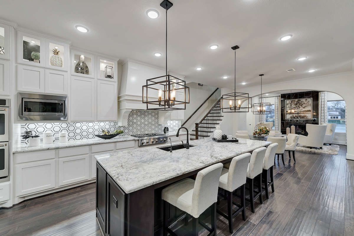 A kitchen with white cabinets , granite counter tops , stainless steel appliances and a large island.