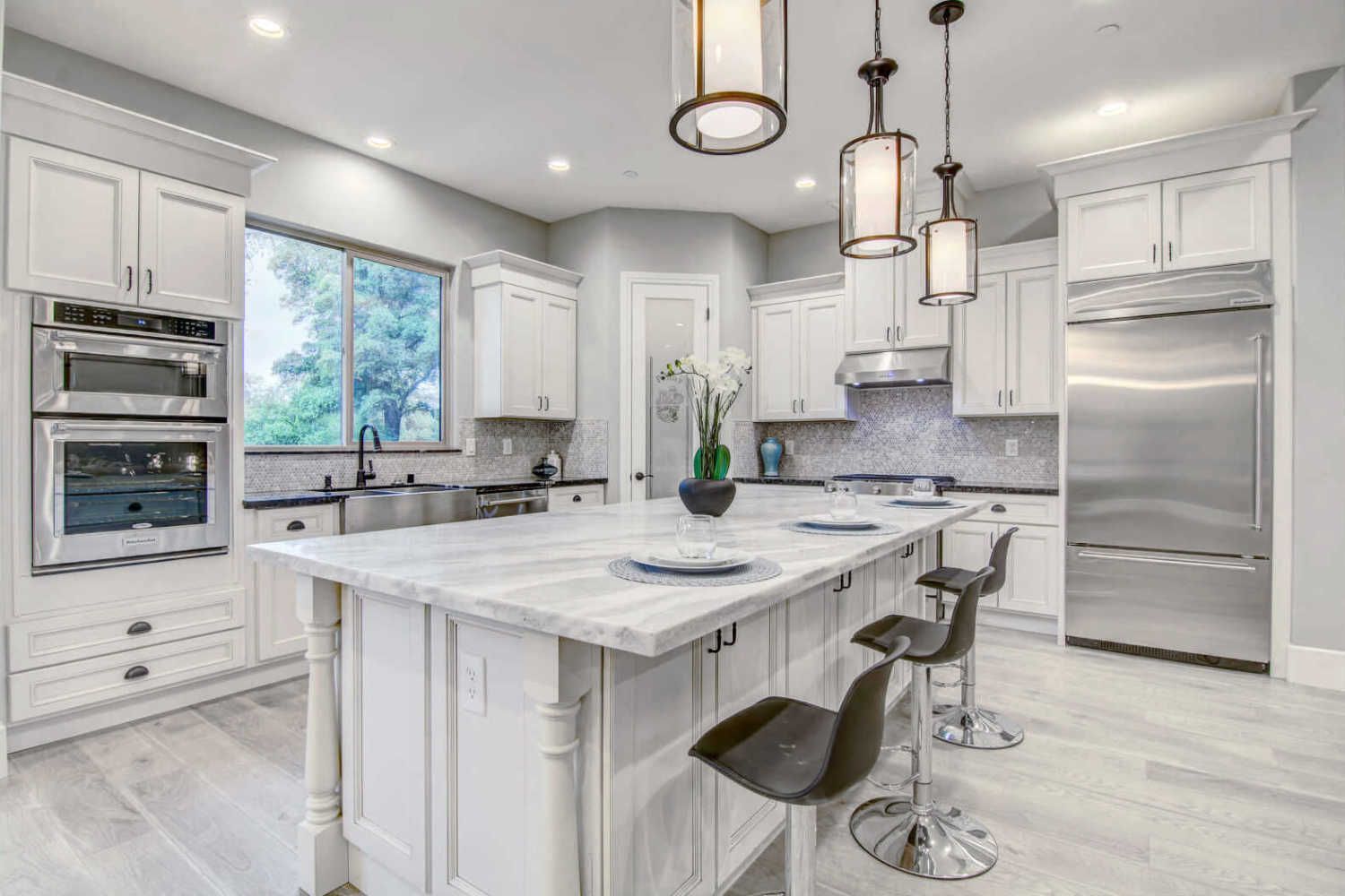 A kitchen with white cabinets , stainless steel appliances , and a large island.