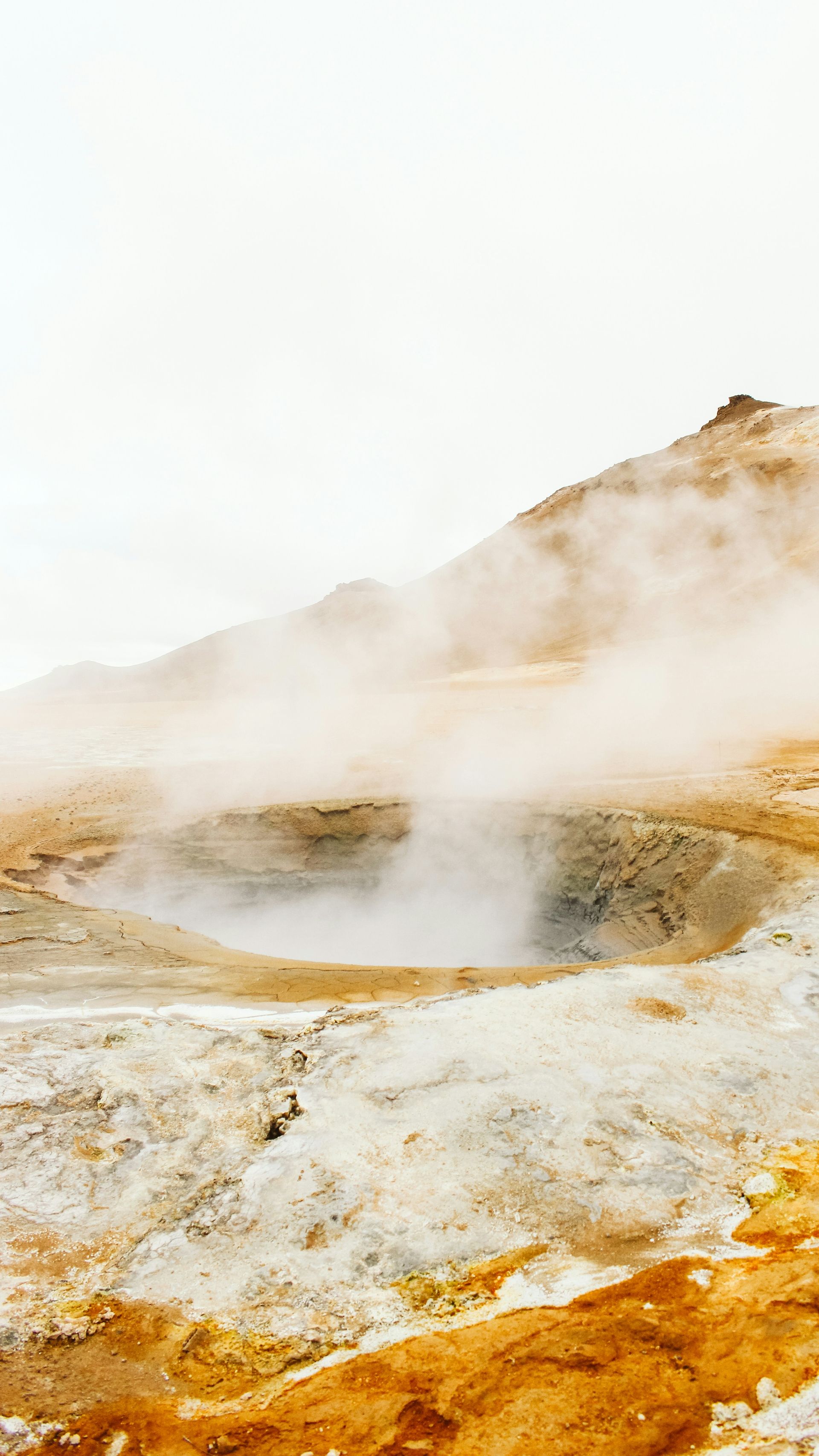 A foggy, steamy hydrothermal landscape in Iceland with yellowish terrain in the foreground.